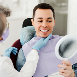 Man smiling at reflection in mirror with dentist