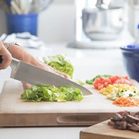 Close up of patient cutting lettuce in her kitchen