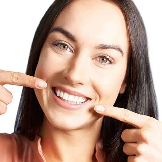 Woman with an attractive smile pointing to teeth