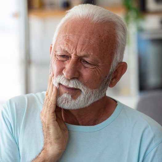 a man touching his cheek due to tooth pain