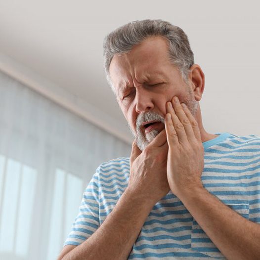 a man touching his cheek due to a failed implant